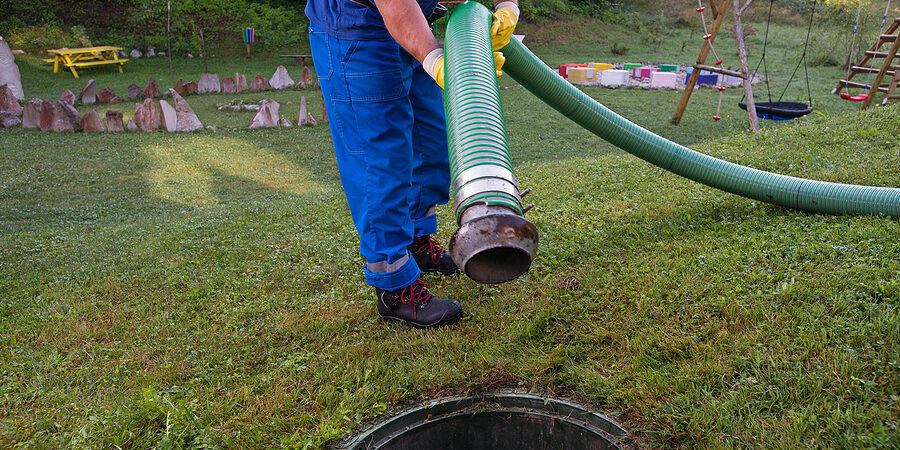 a man in a blue uniform is using a hose to clean a sewer