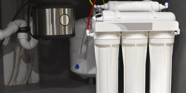 B House water filtration system. Osmosis deionization system. Installation of water purification filters under kitchen sink in cupboard. Clear water concept. Small sharpness, possible granularity