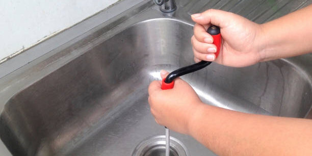 Drain cleaning 2 Woman's hand are breaking through the pipes. Clog pipe cleaner by yourself. Flexible spring drain cleaner.